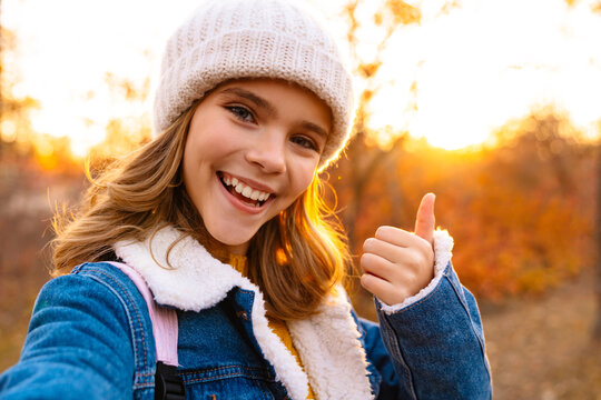 Girl outdoors in autumn park taking a selfie