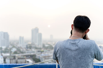 Fototapeta premium Asian photographer man is using his Dslr or mirrorless camera to take pictures of cityscape with the Sunrise or sunset