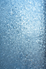 Vertical image of a winter background on a transparent glass window with a frozen texture. Abstract texture background, vertical photo, copy space for your design or text