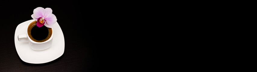 cup of coffee and orchid flower on a dark background