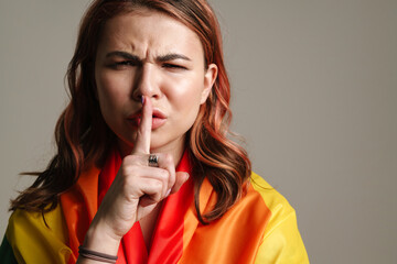Displeased woman wearing rainbow flag showing silence gesture