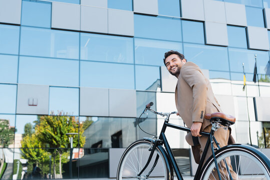 happy businessman in wireless earphones walking on stairs with bicycle
