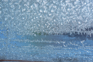 Winter background on a transparent glass of a window with a frozen texture. Abstract texture...