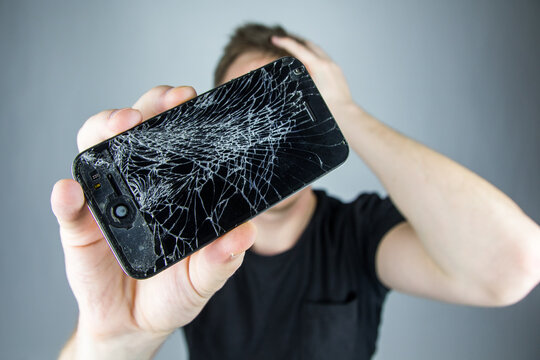 Cracked screen smartphone. Man holds broken iphone