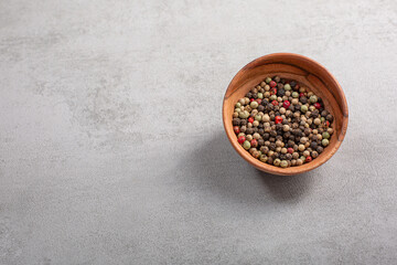Fototapeta na wymiar Pepper spice in a wooden bowl on grey background