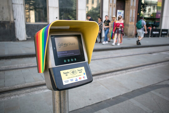 Ticket purchase validation point machine on metal pole on pavement for public transport.  Pride rainbow symbol on top
