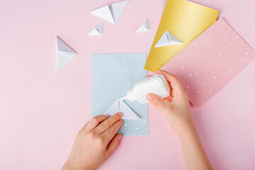 Concept of DIY and kid's creativity, origami. Step by step instruction: how to make greeting cards with christmas trees origami. Step5 Glue the triangles to postcard. New year craft