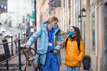 Woman healthcare worker outdoors on the way to work with schoolgirl daughter, coronavirus concept.