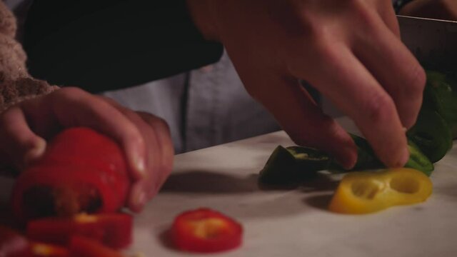 two children sister and brother, cooking at home in the evening. Girl and boy preparing dinner on the table, hands cut vegetable with knife. Father pick up a piece of sweet pepper. Cooking in the fami