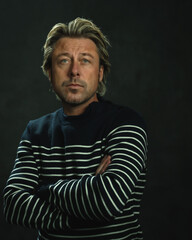 Man with blonde hair in striped fisherman's sweater. Studio portrait.