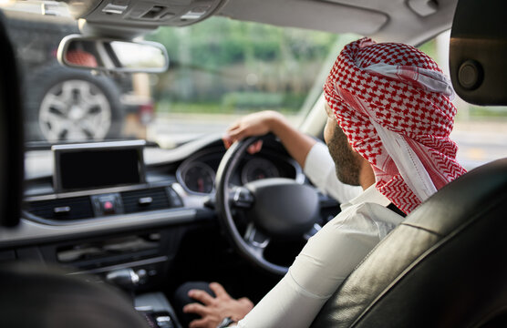 Rear view of arab man driving car in traffic wearing a keffiyeh