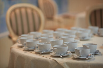 Concept of tea, cups with saucers and spoons on a table with a white tablecloth