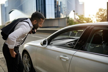 Fototapeta na wymiar Bearded Indian businessman talking to ehailing taxi Driver in city