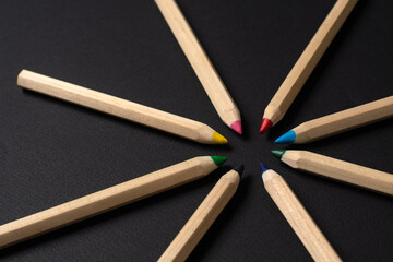 Light pencils on a black background. The pencils are arranged in a circle. Selective focus.