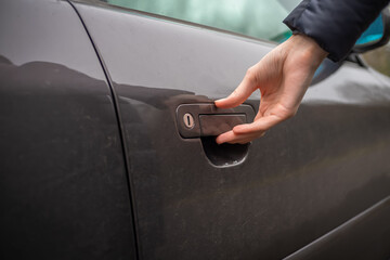 Close-up of a woman's right hand holding the handle of the car and wants to open it