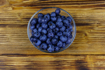 Fresh blueberry in glass bowl on a wooden table. Top view