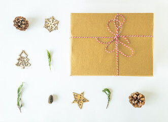 Arrangement of wooden christmas ornaments, pine cones and pine branches with a christmas present box on an isolated white surface, top view