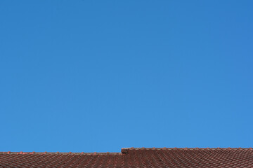 Red roof with tiles and the moon on sunny day with blue sky background. Nature landscape.