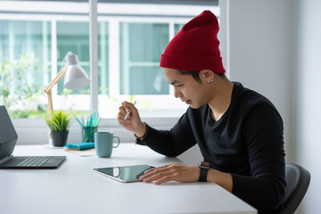 Young asian businessman working at home with tablet on desk.