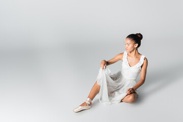 Obraz premium graceful african american ballerina in dress dancing on floor on white background