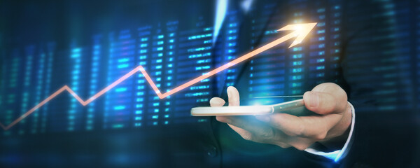 Hand holding smartphone device and touching screen. businessman trader looking on with graphs analysis candle