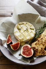 Baked Brie cheese with honey and fresh figs, gallettes and nuts on wooden table. Selective focus