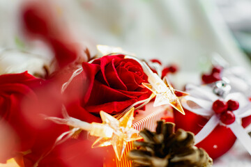 Christmas decorations on a soft cozy white blanket. Red toys in the form of balls and berries, with fir cones. Around yellow lanterns light bulbs in the form of stars. Elegant composition for Christma