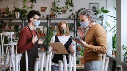Frustrated owner, manager talking to waiter in closed cafe, small business lockdown due to coronavirus.