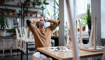 Frustrated owner sitting at table in closed cafe, small business lockdown due to coronavirus.