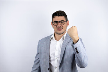 Business young man wearing a casual shirt over white background angry and mad raising fist frustrated and furious while shouting with anger. Rage and aggressive concept.