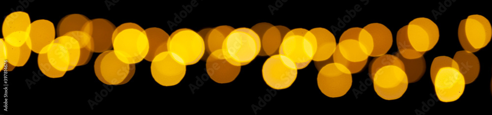 Poster yellow bokeh lights on a black background. abstract shiny pattern in defocus.