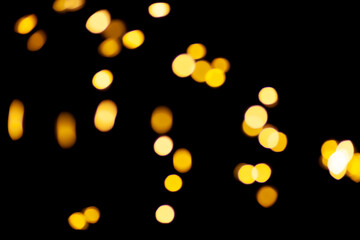Gold lights garland in defocus on a black background. Yellow circles bokeh.