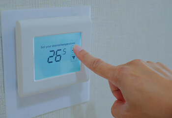 Hand press the touch screen panel of air conditioner to increase the tenperature. Energy saving...