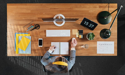 Top view of female student working on computer at desk at home.