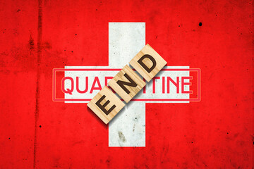 Obraz premium End of quarantine. The inscription on wooden blocks on the background of the flag of Switzerland. The end of the pandemic. Business.
