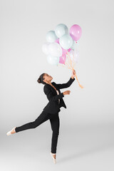 african american businesswoman performing ballet with balloons isolated on grey