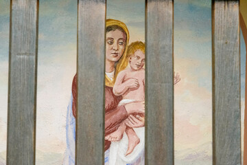 Painting of madonna with child. Wooden grate of a mountain capital.