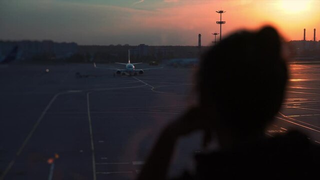 sad traveller stands at the airport window. Airplanes canceled empty runway and lounge, Empty Airport terminal clossed hall, international departure in coronavirus pandemic. Empty seats with no people