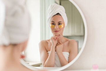 Young beautiful woman with silicone gold eye patches. Facial care at home. Girl with clean skin....