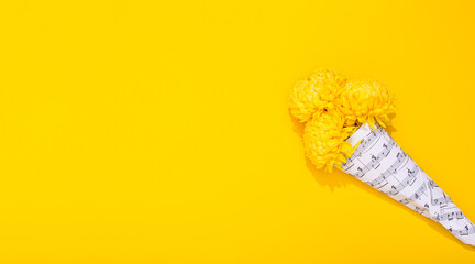 Bouquet of three lush chrysanthemums wrapped in a sheet with musical notes on yellow background. A holiday theme of music lovers. Happy Valentine Day February 14. Woman Day March 8. Mother Day May 8