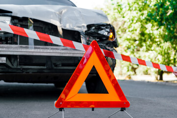 Police tape and Red emergency stop triangle sign on road in front of car accident. Broken Suv car...