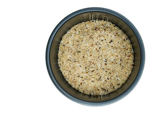 Isolated electric rice cooker with raw mix brown rice inside, top view electric rice cooker with brown rice on white background. Sand texture on inner pot.