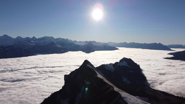 the bernese mountains (in switzerland) under the thick layer of fog, above blue sky and sun