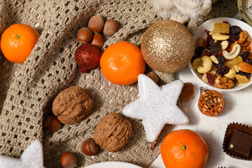 sweet food background for christmas or holiday decoration - chocolate candies, tangerines, nuts and dried fruits on white wood