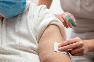 senior adult elderly woman with grey hair is receiving a vaccination against covid