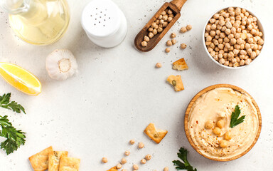 Flatlay Hummus in a wooden plate and raw chickpeas in a bowl. Dishes of chickpeas, a vegetarian dish. Copy space.