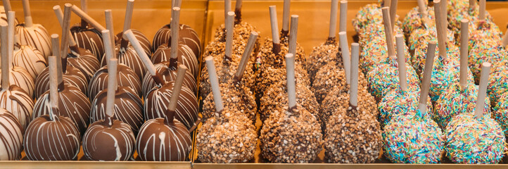 Caramel apples with nuts in glaze and chocolate on a tray at the fair