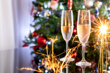 TWO CHAMPAGNE BOWLS ON A DARK GLASS TABLE IN FRONT OF A CHRISTMAS TREE, ESPARLK CLOSE THE BOWLS