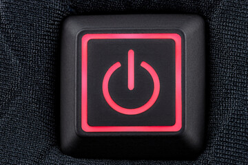 Macro shot of a plastic button with a red power symbol, sewn into modern clothing, top view.