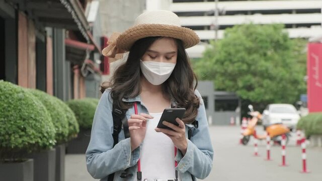 asian female traveller casual cloth wear face mask protection with backpack walking in the city during epidemic corona virus(covid 2019) infection.New Normal and social distancing concept